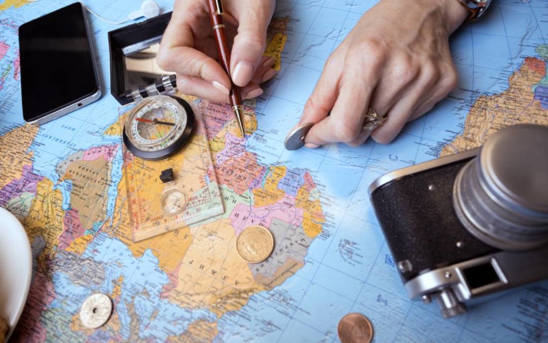 A persons using a map, compass, and pen to plan a trip around the world.