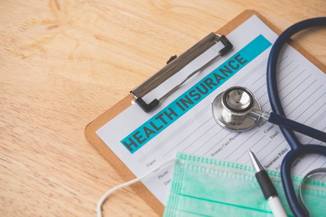 Clipboard with a health information sheet, medical mask, and stethoscope sit on top of a desk