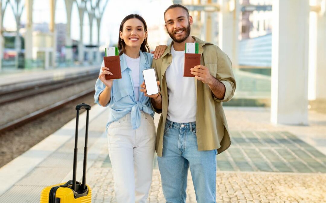 A man and woman with their luggage hold up their passports an plane tickets.