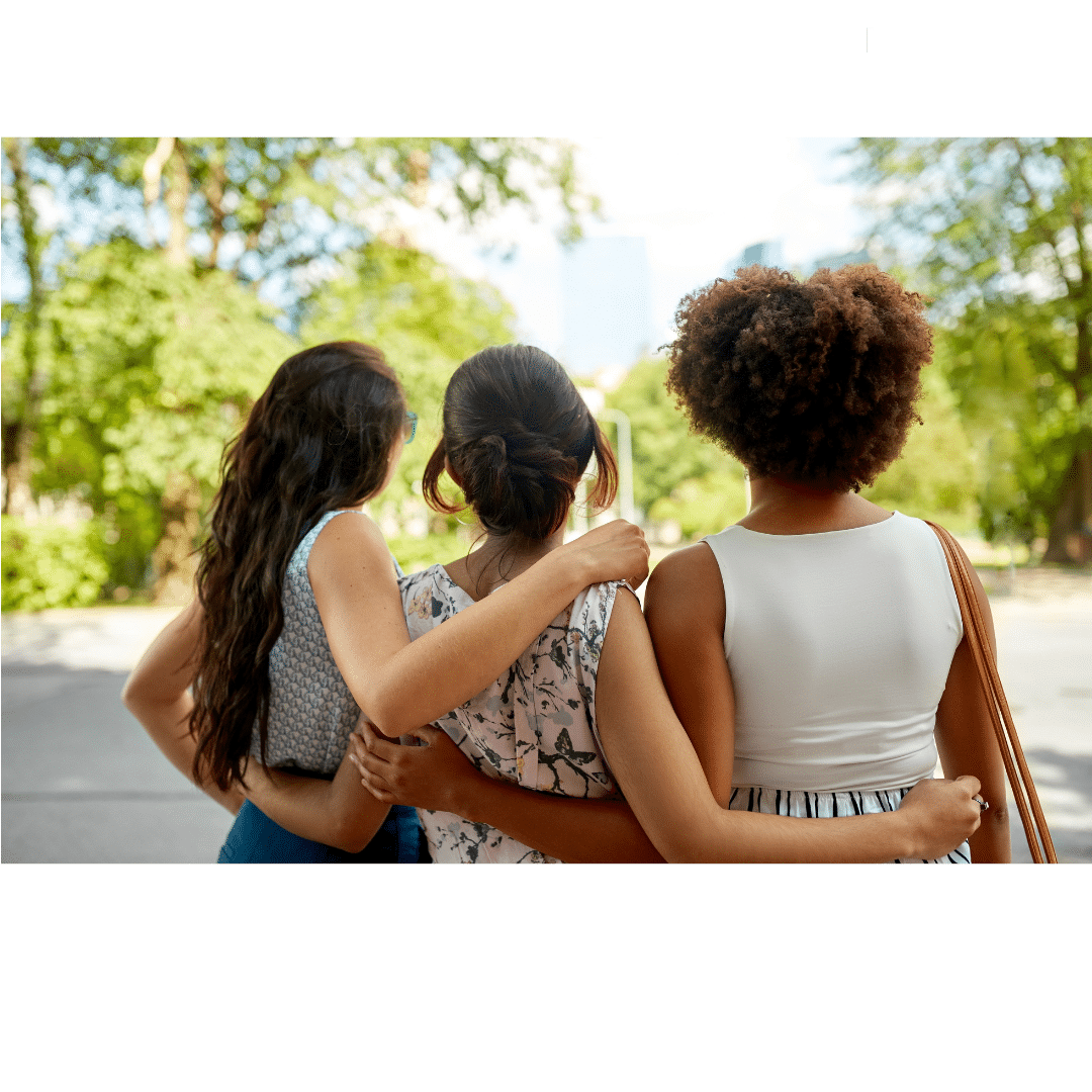 Three women of different ethnicities wrap their arms around each other